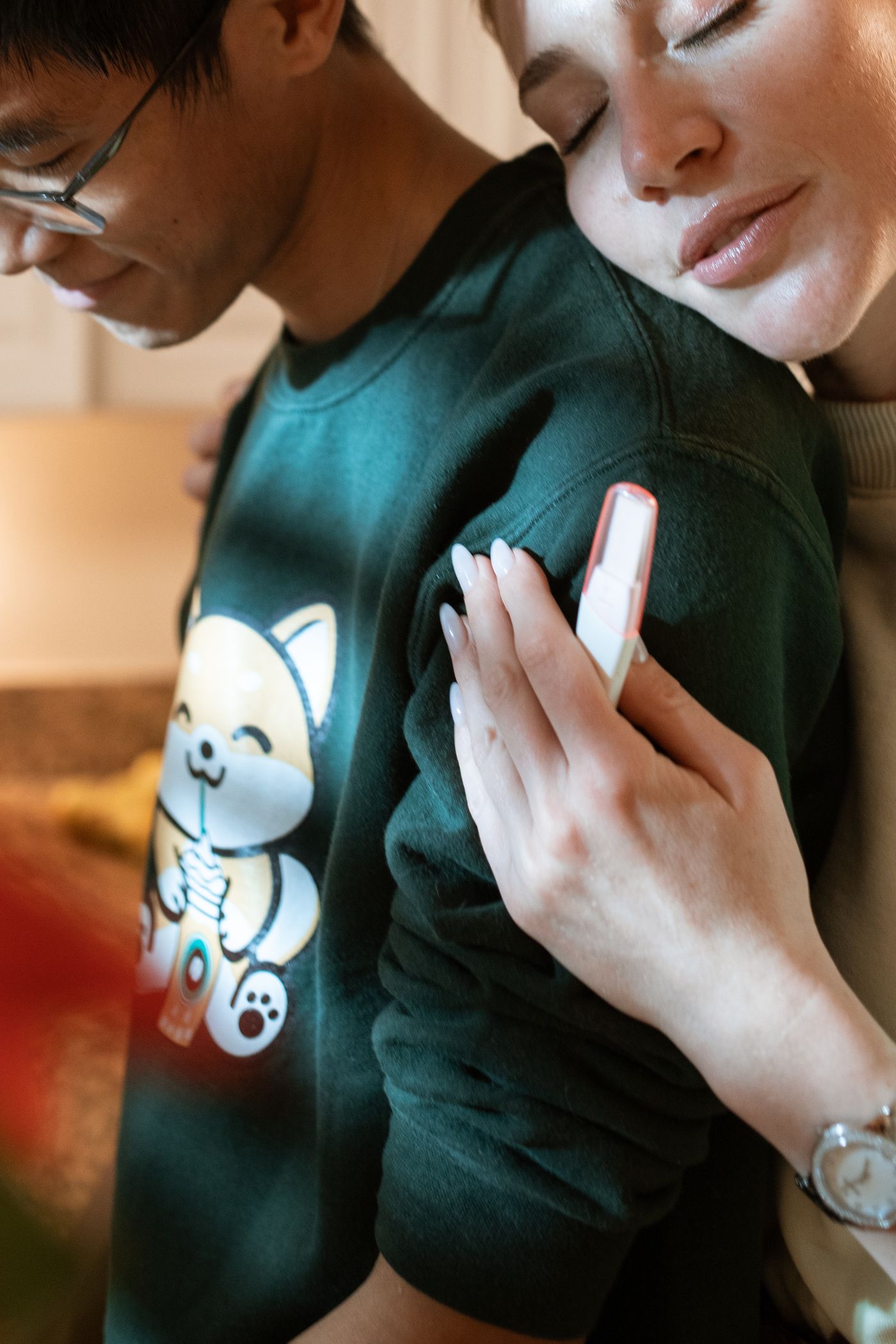 A woman holding a positive pregnancy test embracing her husband — the joy and disbelief of discovering you are pregnant for the first time