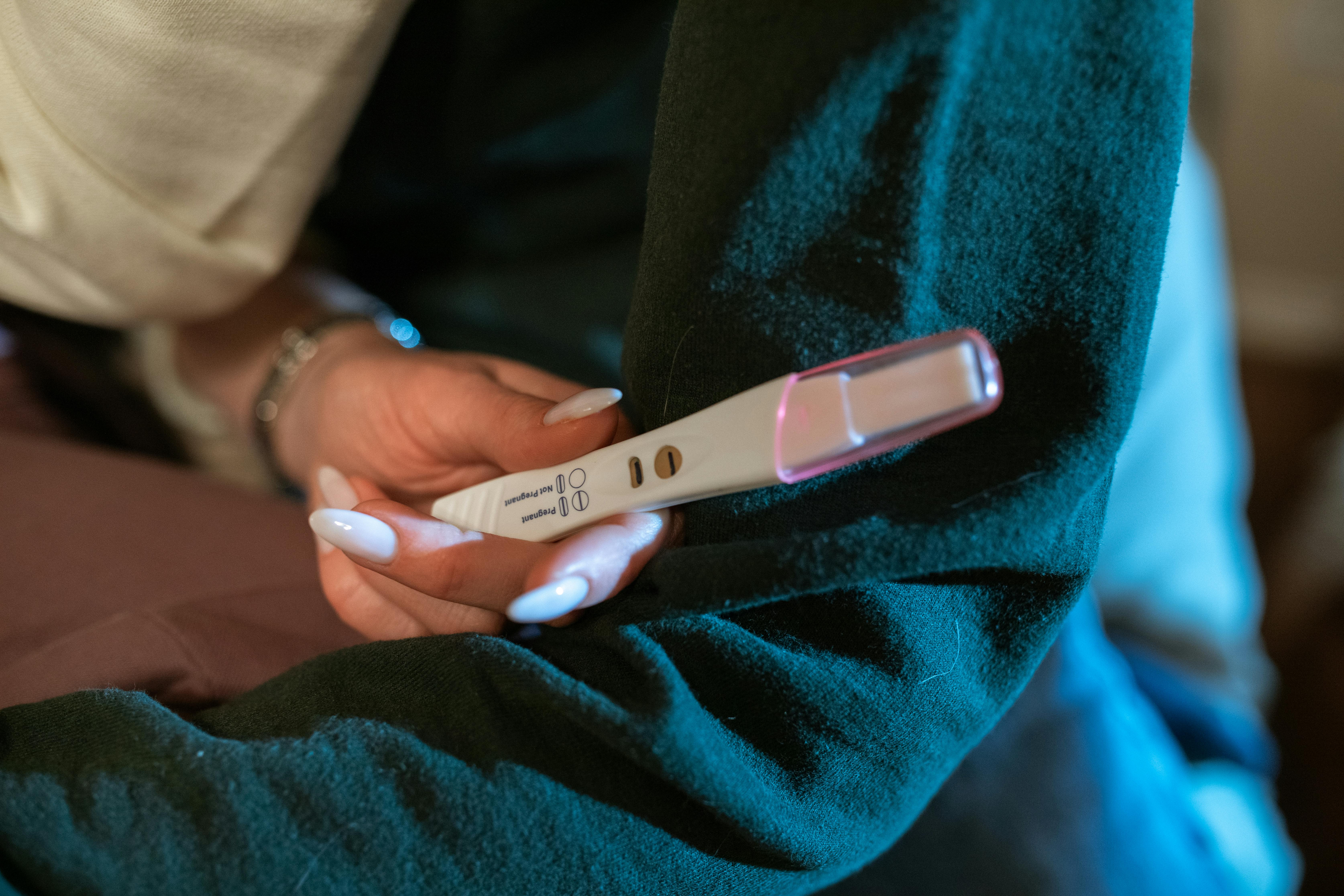 a woman holding a pregnancy test with positive result