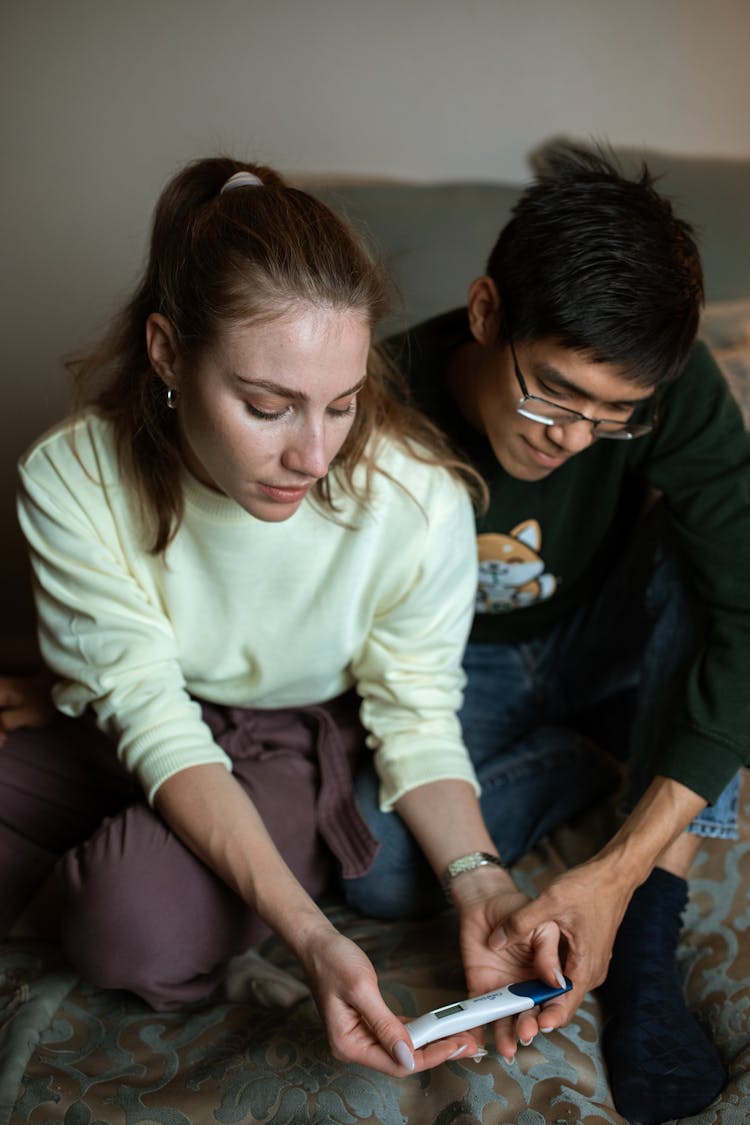 A Woman Holding A Pregnancy Test Kit Beside A Man