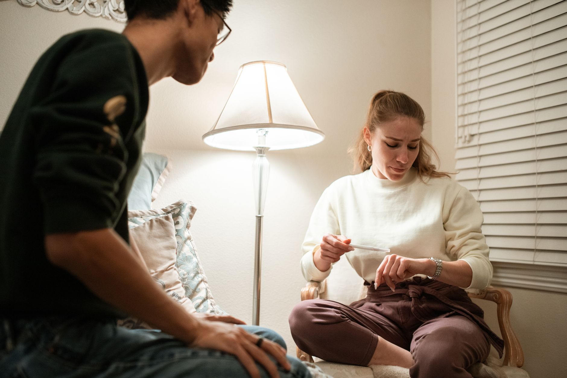 A couple in a cozy living room discussing a pregnancy test result, highlighting anticipation.