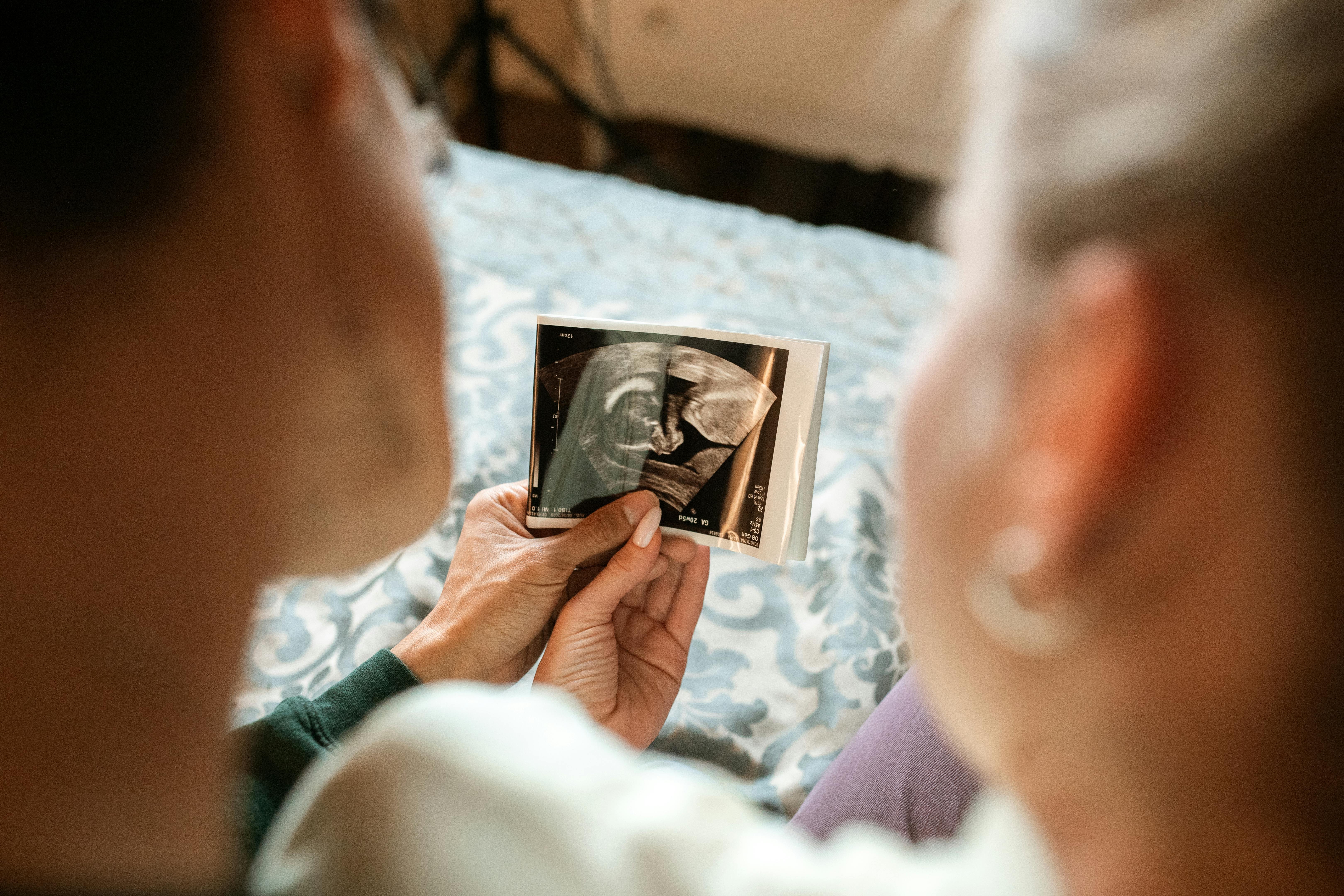 woman in white long sleeve shirt holding photo of man in black suit