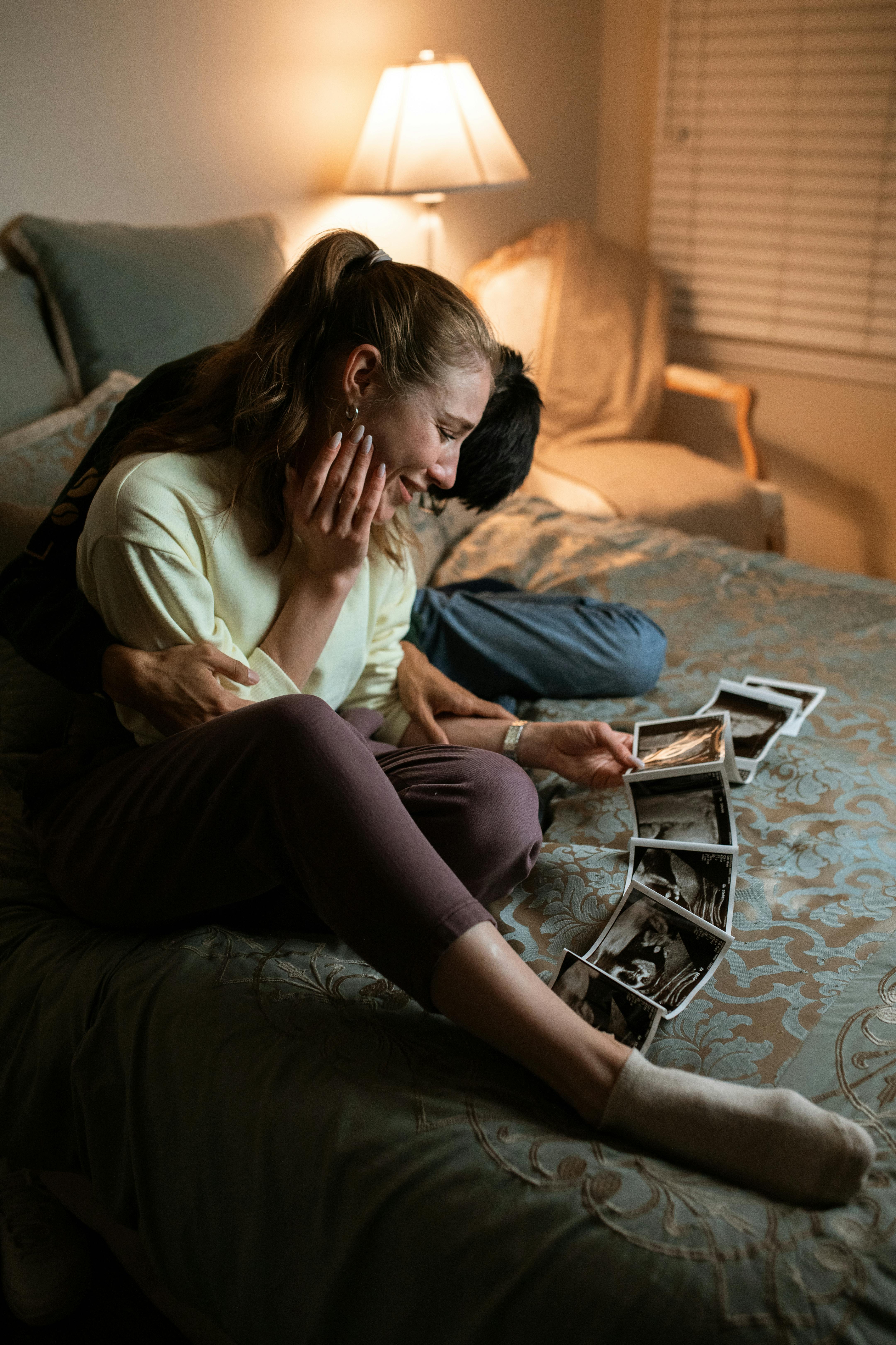 woman in white shirt and black pants sitting on bed