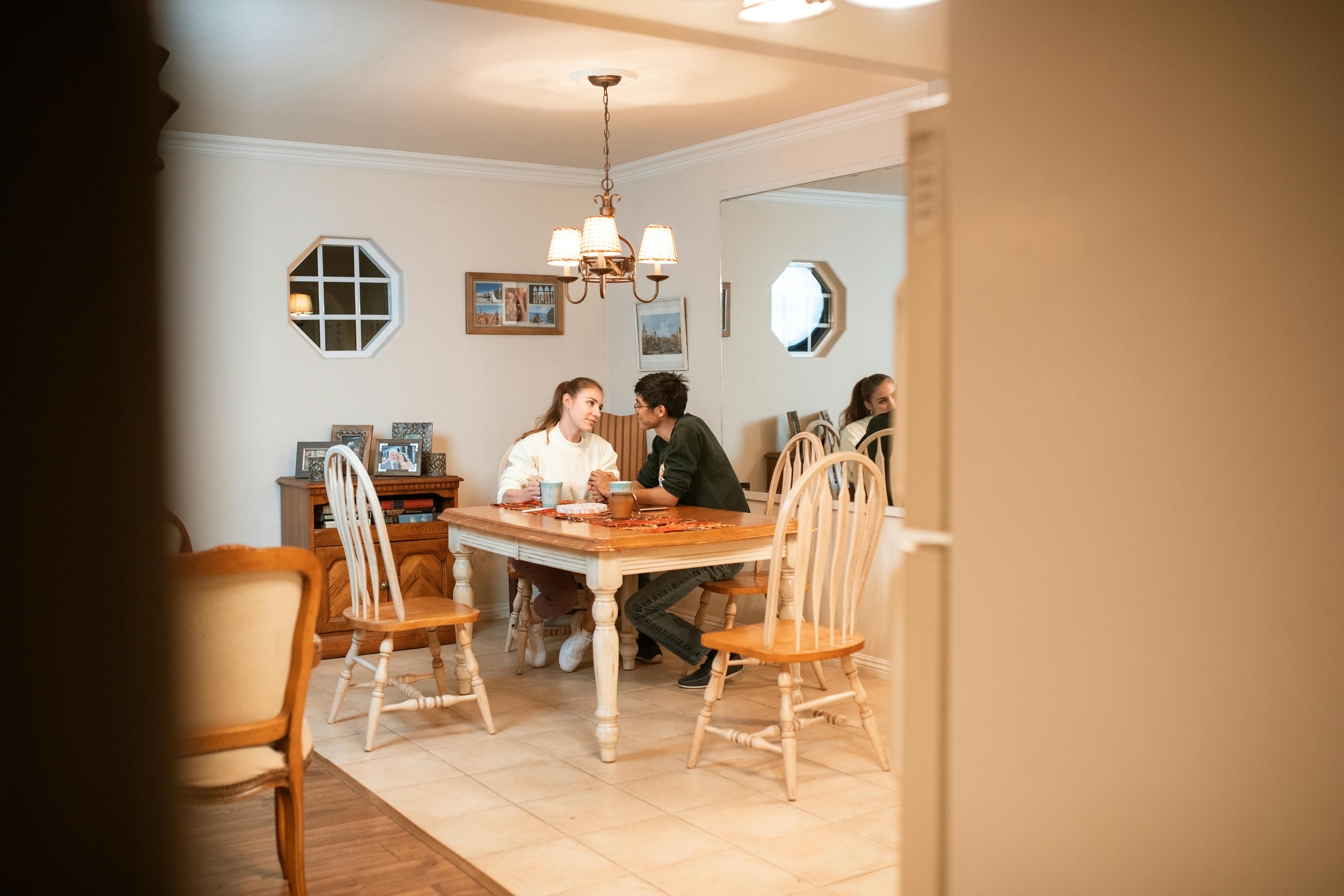 man and woman sitting on dining table talking