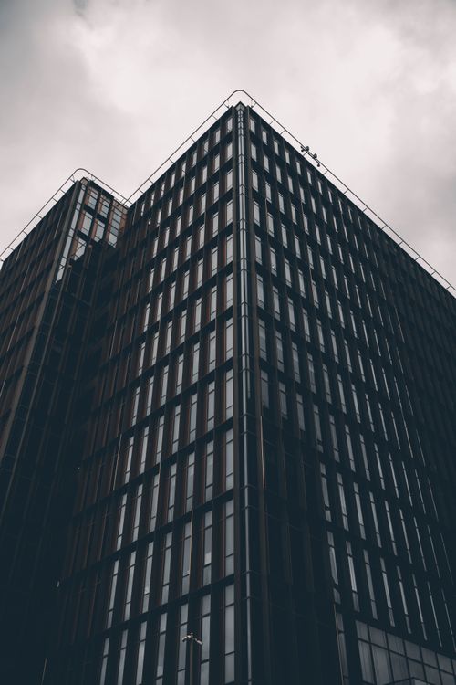 Free Low-angle view of a modern skyscraper with a moody, overcast sky. Stock Photo