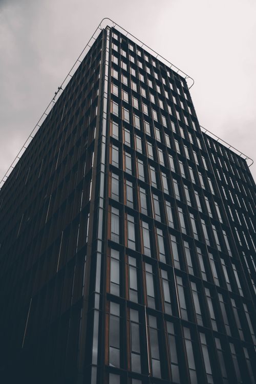 Free Contemporary office tower with grid-like facade in overcast sky, low angle view. Stock Photo