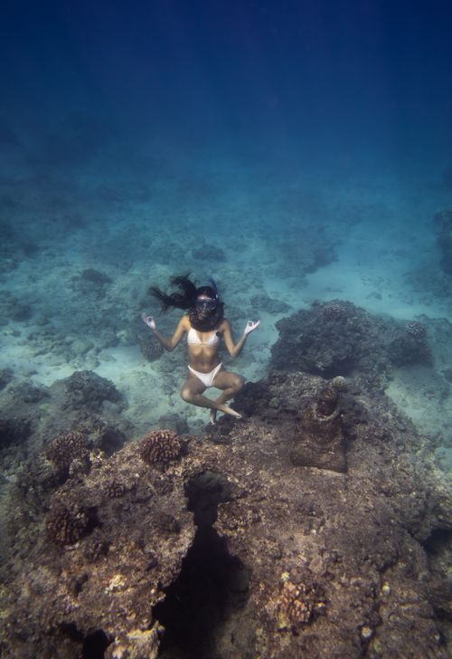Free High angle full body of woman in swimsuit and snorkeling mask with flippers doing Lotus pose and Mudra gesture swimming undersea Stock Photo