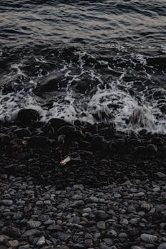 Dark waves crash onto the rocky shore of Funchal, Madeira creating a dramatic seascape view.