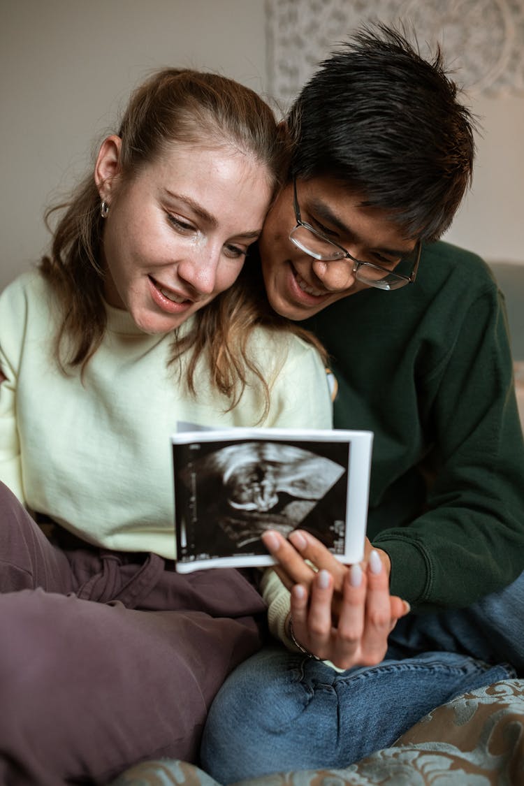 A Couple Happily Looking At An Ultrasound Result