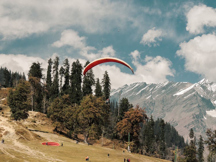 People Paragliding In Mountain Valley