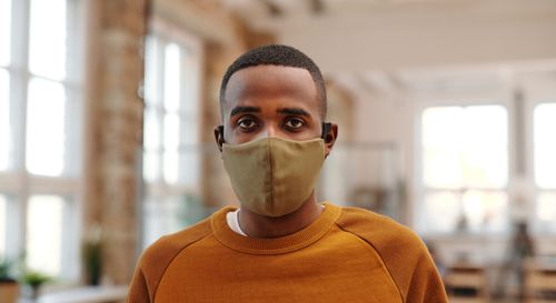 Free Close-up of young man wearing a face mask indoors, promoting personal protection and safety. Stock Photo