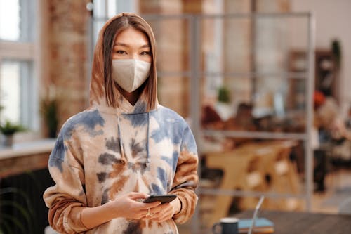 Free A Woman Wearing a Printed Hoodie Sweater and Facemask Stock Photo