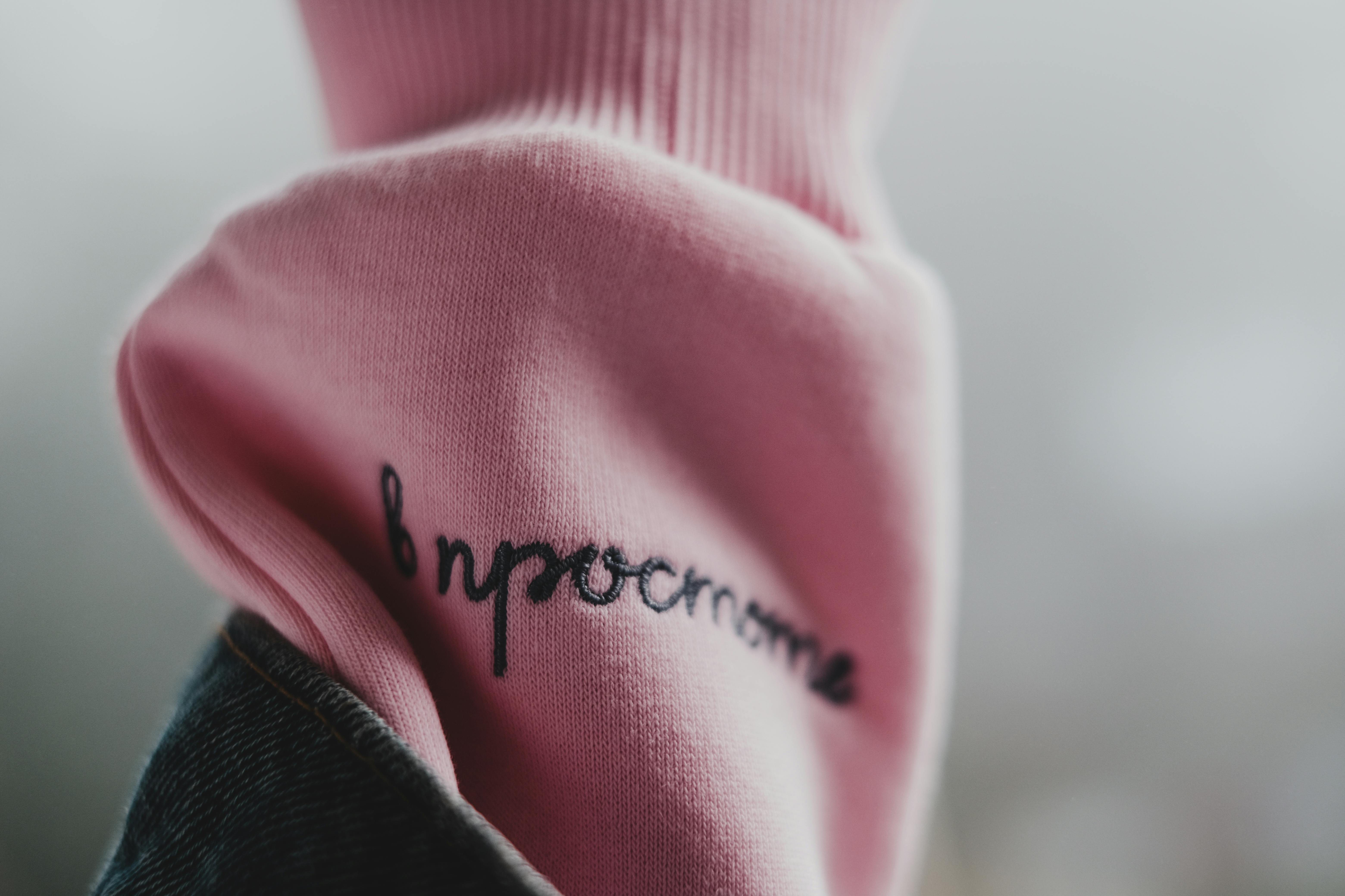 Detailed view of a pink sweater sleeve with black embroidery, featuring soft textures.