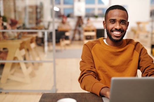 Confident man in brown sweater working on laptop in cozy office.