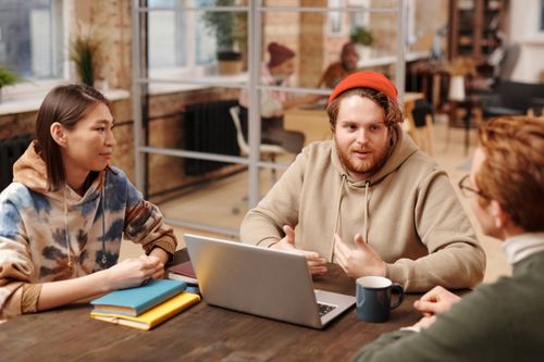Free Coworkers engage in a collaborative meeting around a laptop in a modern office setting. Stock Photo