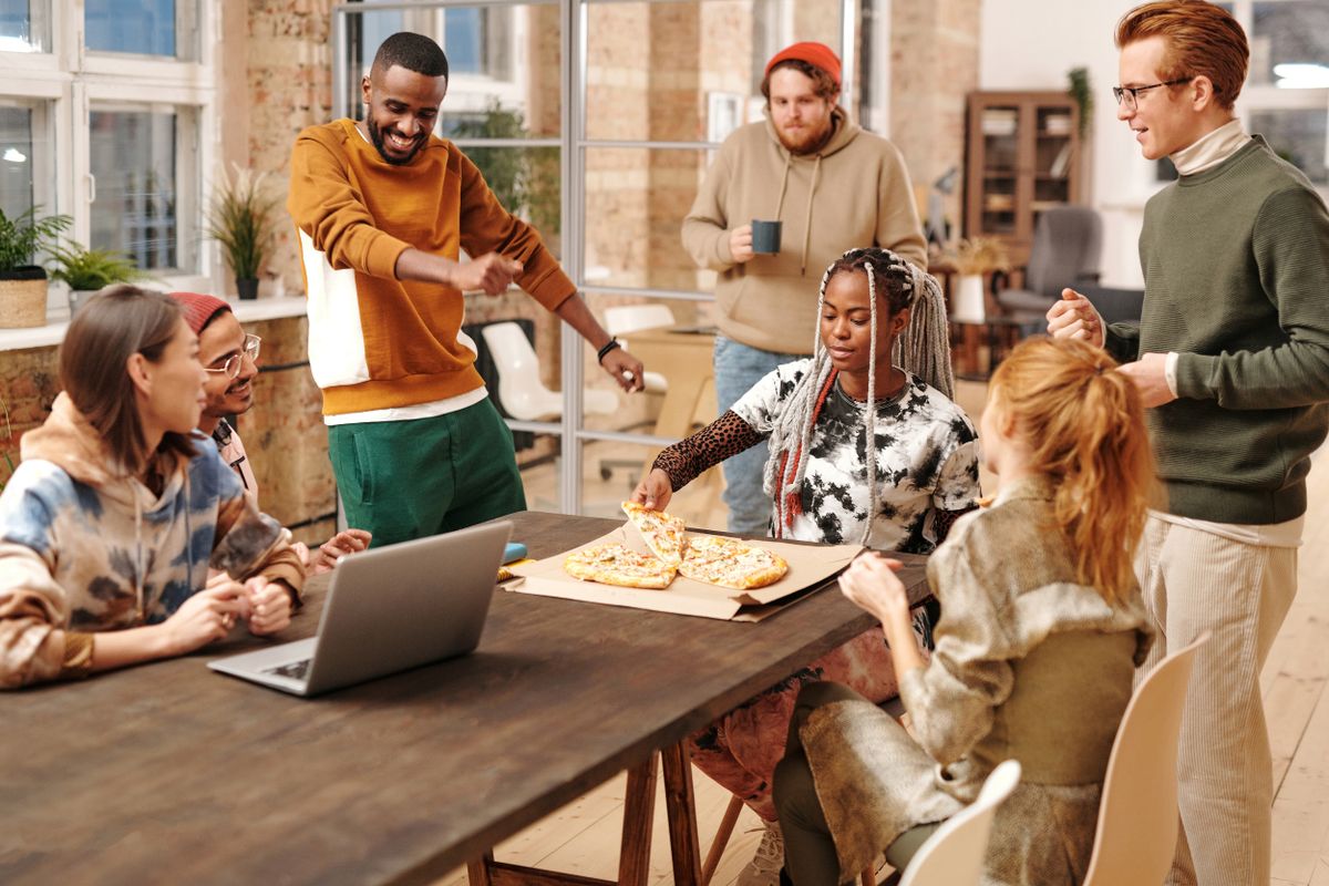 Diverse group of smiling young adults sharing a meal and laughing together at home