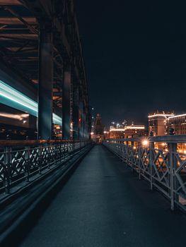 Night view of an illuminated cityscape with a modern bridge and train in motion.