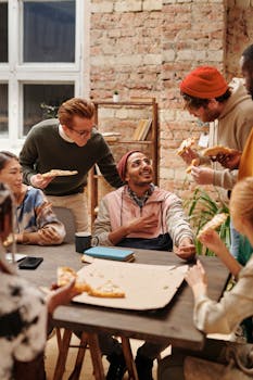 A diverse group of coworkers enjoying pizza and conversation in a modern office.
