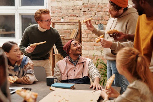 Group of diverse adults enjoying pizza during a casual office meeting.