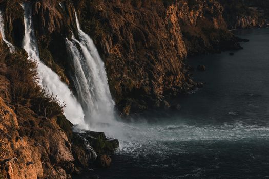 Dramatic waterfall plunging into the blue-green waters below, framed by rugged cliffs.
