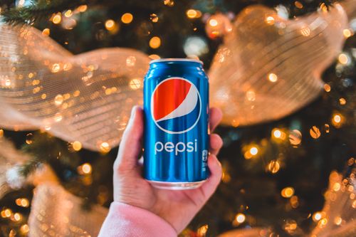 Free Crop unrecognizable person showing colorful can of refreshing drink during New Year holiday Stock Photo