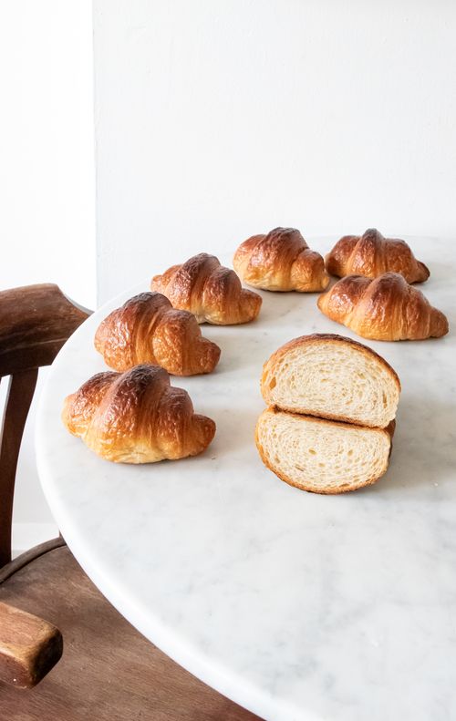 Free Delicious homemade croissants on a marble table, showcasing their golden crust and soft interior. Stock Photo