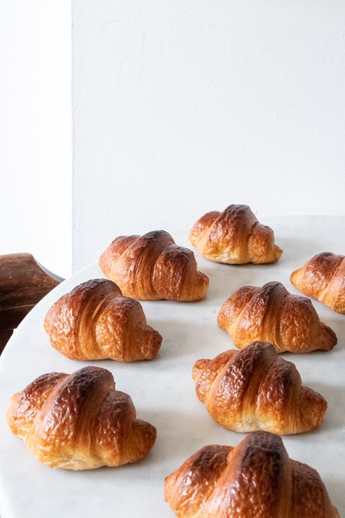 Free Delicious freshly baked croissants on a white marble table, perfect for gourmet breakfast imagery. Stock Photo