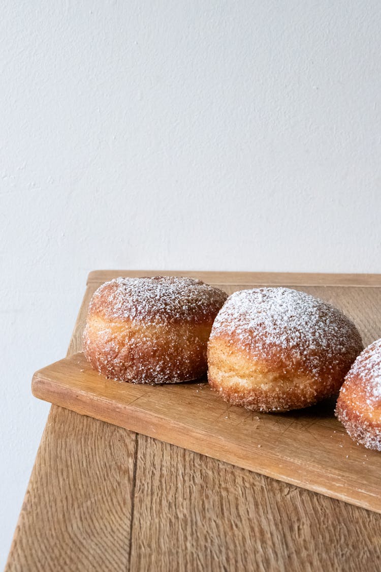 Powdered Paczki On Wooden Cutting Board