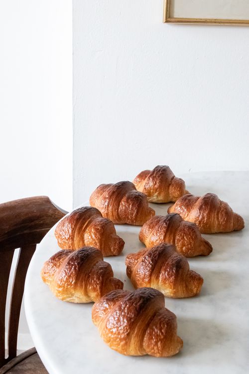 Free Freshly baked croissants arranged on a marble table in a cozy London bakery. Stock Photo