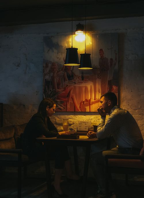 Free Couple enjoying a relaxed dinner under warm lighting in a cozy restaurant setting. Stock Photo