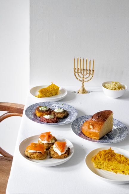 Jewish cuisine featuring traditional Hanukkah dishes and a menorah on a dining table.