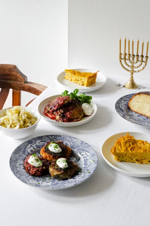 Free A beautifully arranged Hanukkah meal featuring latkes, kugel, and a menorah centerpiece. Stock Photo