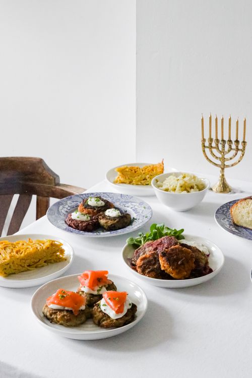 Free Celebrate Hanukkah with a delicious spread of Jewish cuisine featuring latkes, kugel, and a menorah centerpiece. Stock Photo