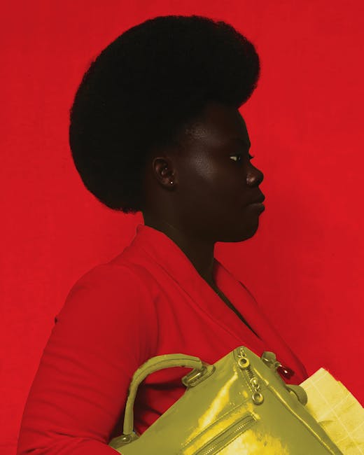 Side view of African American female with yellow bag looking away while standing against red background