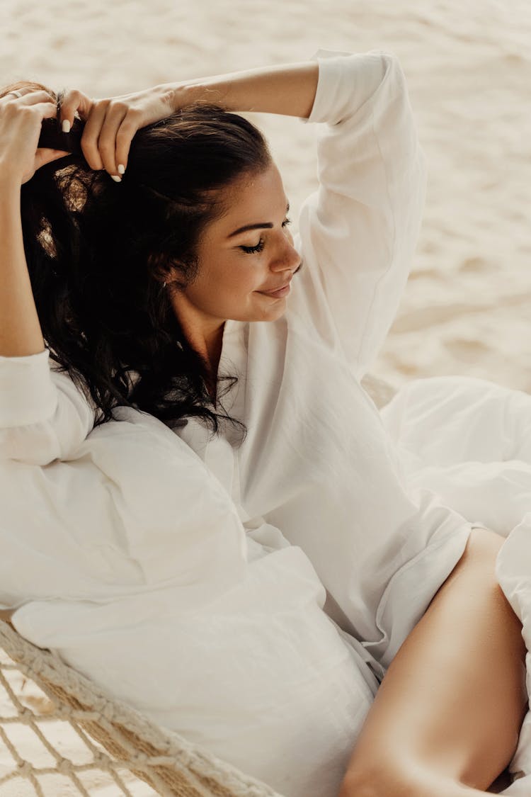 Close-Up Shot Of A Woman In White Long Sleeve Tying Her Hair