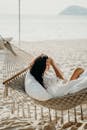 宁静的女人躺在阳光明媚的巴厘岛海滩的吊床上，享受着夏日的时光