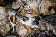 From above of fresh fast curvy stream of mountain water flowing through big slick stones