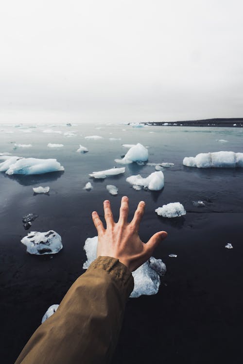 Crop person admiring view of cold ocean