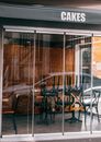 Exterior of modern cafe terrace with glass walls and chairs placed upside down on table