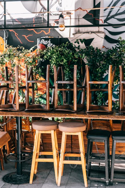 Free Chairs placed on table near green plants and glass wall on veranda of modern outdoor cafeteria on street in city Stock Photo