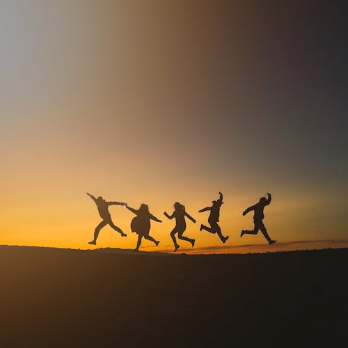 Силуэт людей, прыгающих во время заката