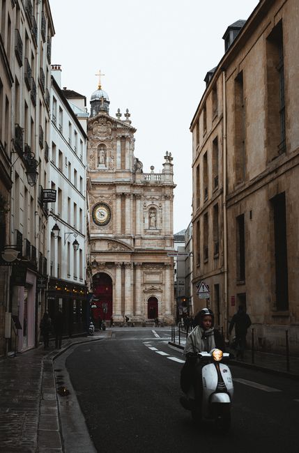 Old classic buildings located on narrow paved street with pedestrians in European city