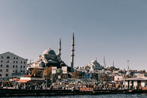 Medieval Hagia Sophia cathedral with dome located on crowded embankment near sea in Istanbul city in Turkey against blue sky