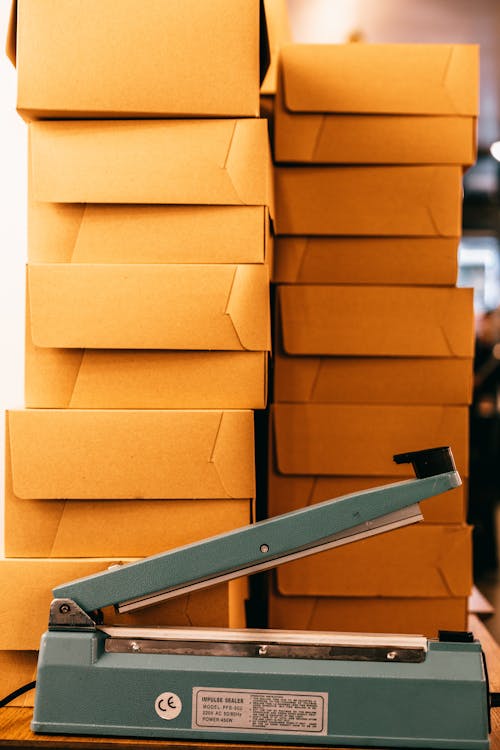 Bag sealer near piles of cardboard boxes in storehouse