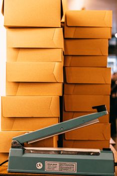 Bag sealer with information on sticker near heaps of similar carton boxes in industrial building