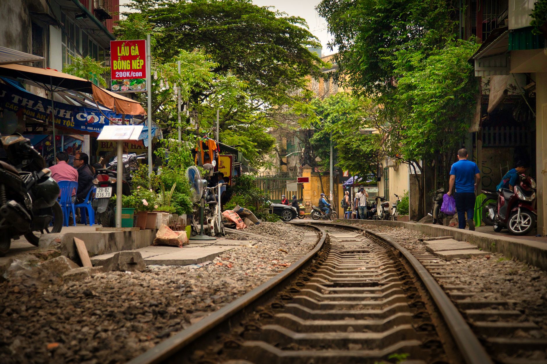 Lebhafte Straßenszene in Hanoi mit städtischen Bahngleisen und dem sich in der Nähe abspielenden Alltag.