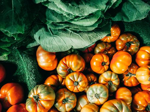 Free Top view composition of ripe green cabbage leaves and organic tomatoes heaped together on vegetable market stall Stock Photo