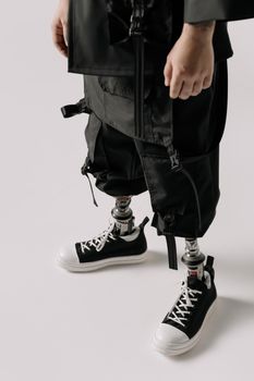 A stylish individual with advanced prosthetic legs wearing trendy sneakers and black outfit.