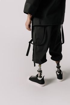Close-up of a person wearing prosthetic legs and stylish attire in a studio setting.
