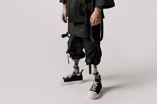 Close-up of a person wearing prosthetic legs, stylishly dressed in a studio setting, focusing on modern fashion.