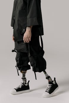 Stylish portrait of individual with prosthetic legs wearing trendy black sneakers and outfit in a studio setting.